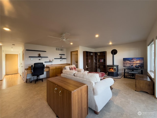 living room featuring ceiling fan and a wood stove