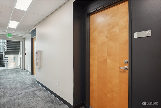 hallway with carpet floors and a drop ceiling