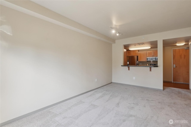 unfurnished living room featuring light colored carpet and track lighting