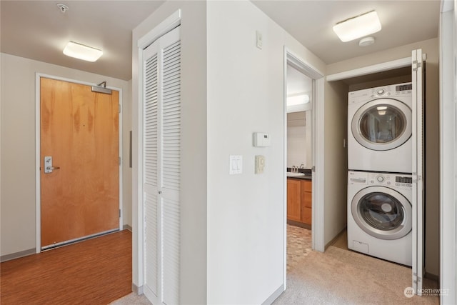 washroom featuring stacked washer and dryer, sink, and light carpet