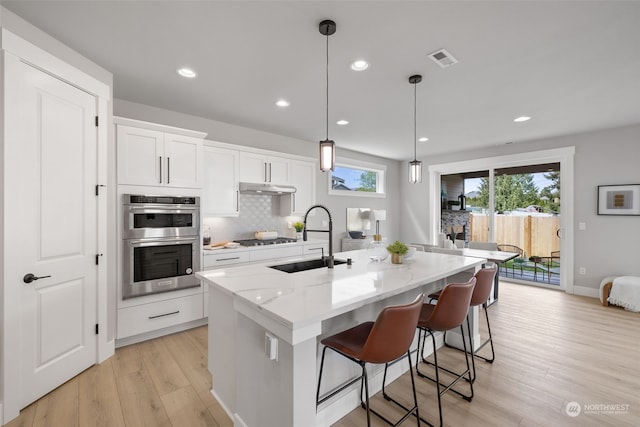 kitchen with sink, white cabinetry, an island with sink, pendant lighting, and stainless steel appliances