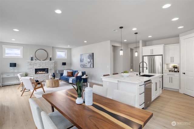 dining room with a stone fireplace, sink, and light hardwood / wood-style floors