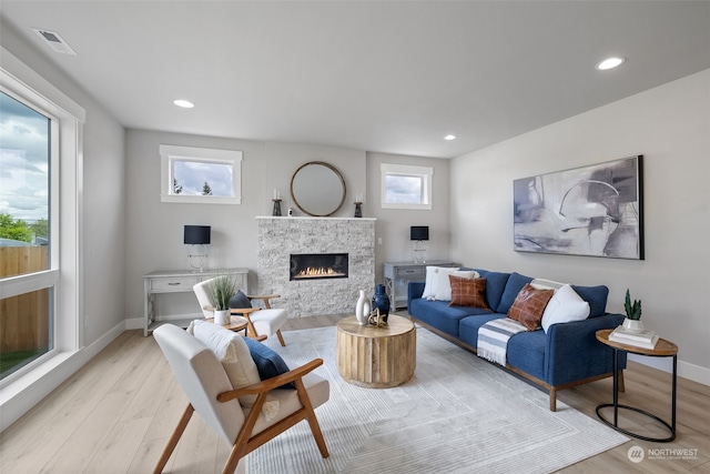 living room with a stone fireplace and light hardwood / wood-style flooring