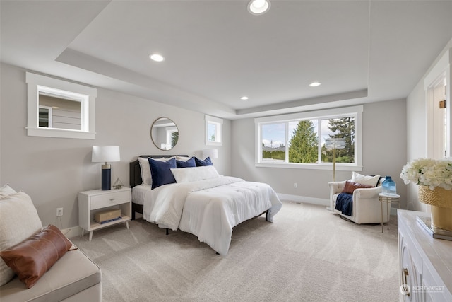 bedroom featuring light carpet and a tray ceiling