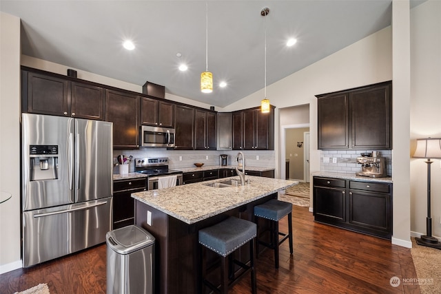 kitchen with lofted ceiling, sink, appliances with stainless steel finishes, pendant lighting, and decorative backsplash