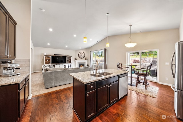 kitchen with sink, dark brown cabinets, appliances with stainless steel finishes, an island with sink, and pendant lighting