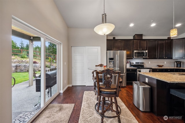 kitchen with light stone counters, hanging light fixtures, dark brown cabinetry, and appliances with stainless steel finishes