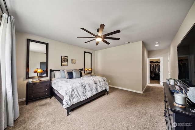 carpeted bedroom with a walk in closet, ceiling fan, and a closet