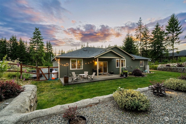 back house at dusk with a patio and a yard