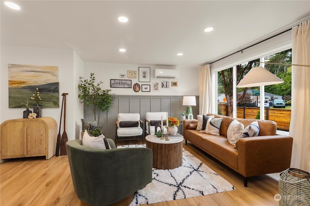 living room with a wall mounted air conditioner and light hardwood / wood-style flooring