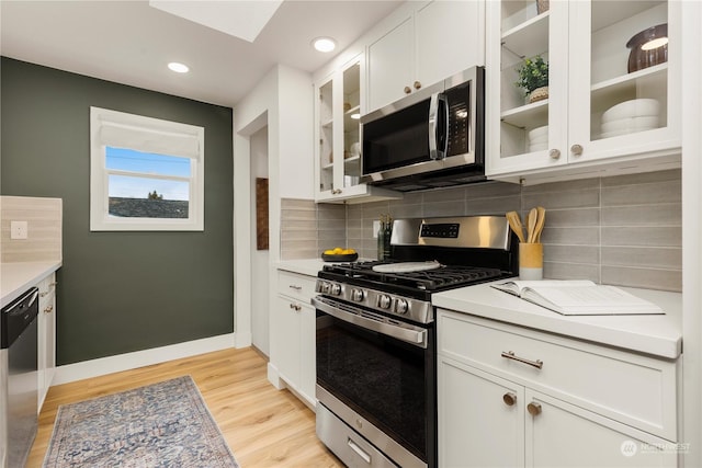 kitchen with white cabinetry, appliances with stainless steel finishes, backsplash, and light hardwood / wood-style floors