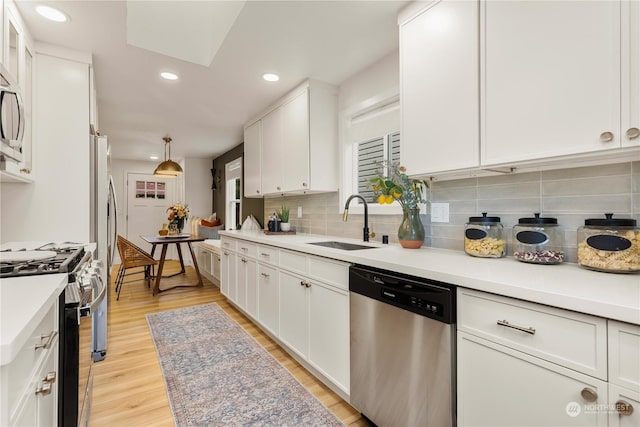 kitchen featuring white cabinetry, appliances with stainless steel finishes, sink, and pendant lighting