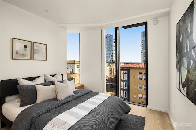 bedroom featuring access to exterior, light hardwood / wood-style floors, and expansive windows