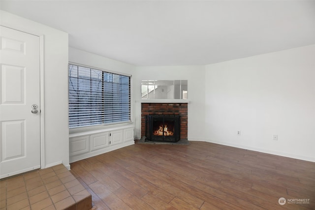 unfurnished living room featuring a brick fireplace and dark hardwood / wood-style flooring