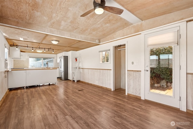 unfurnished living room featuring hardwood / wood-style floors, a wealth of natural light, and track lighting