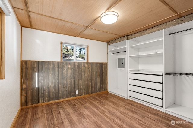 unfurnished bedroom featuring wood walls, wood ceiling, electric panel, a closet, and hardwood / wood-style flooring