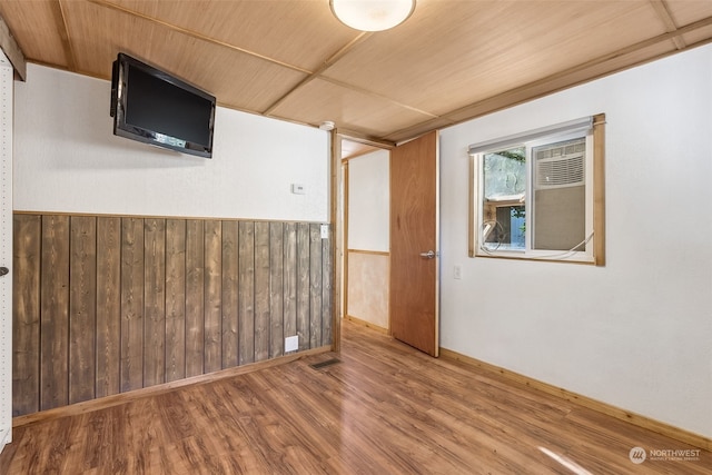 empty room with hardwood / wood-style flooring, wooden ceiling, and wood walls