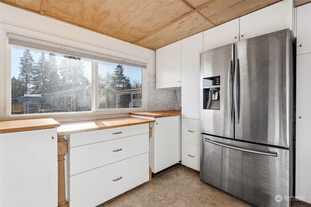 kitchen featuring stainless steel refrigerator with ice dispenser, white cabinetry, wooden counters, and decorative backsplash