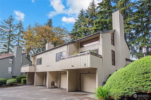 rear view of house featuring a garage and a balcony