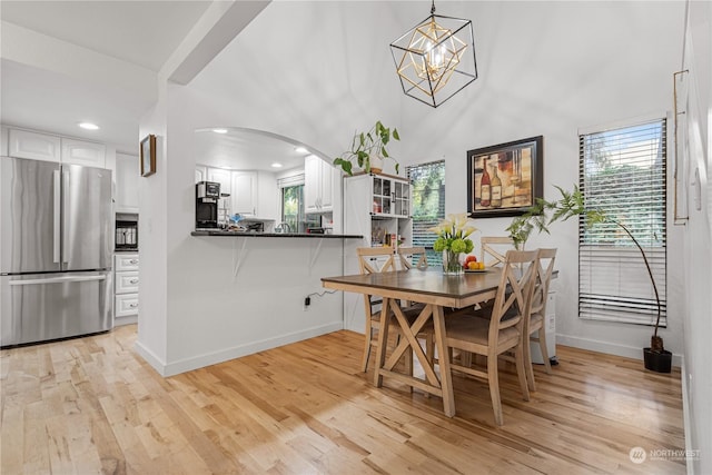 dining area with light hardwood / wood-style floors, a chandelier, and a high ceiling