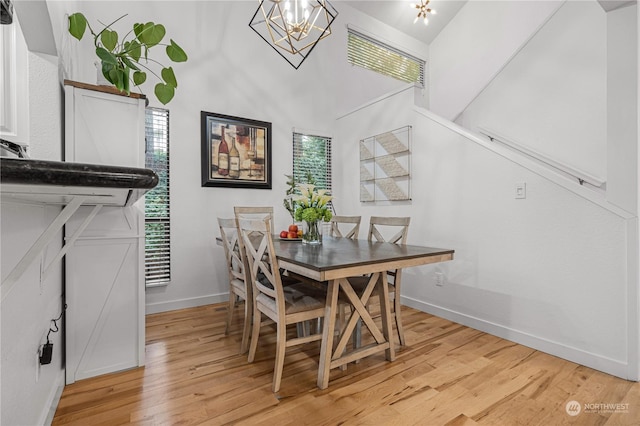 dining area with an inviting chandelier, lofted ceiling, and light hardwood / wood-style flooring