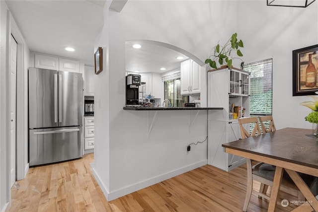 kitchen featuring white cabinetry, stainless steel fridge, light hardwood / wood-style floors, and kitchen peninsula