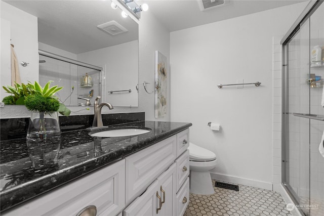 bathroom featuring tile patterned flooring, vanity, an enclosed shower, and toilet