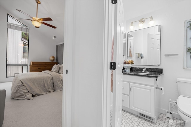 bathroom with ceiling fan, vanity, toilet, and vaulted ceiling