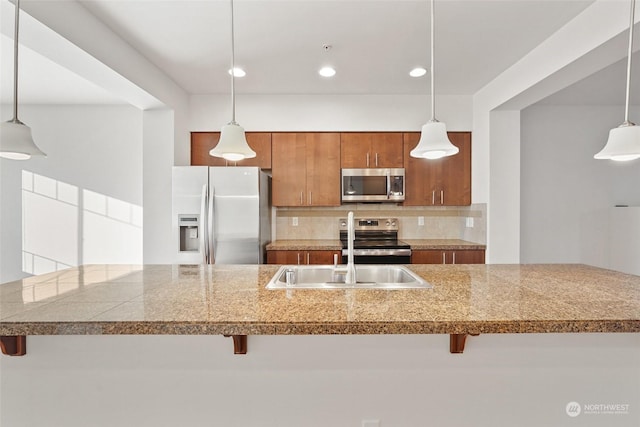 kitchen featuring sink, backsplash, a kitchen breakfast bar, hanging light fixtures, and stainless steel appliances