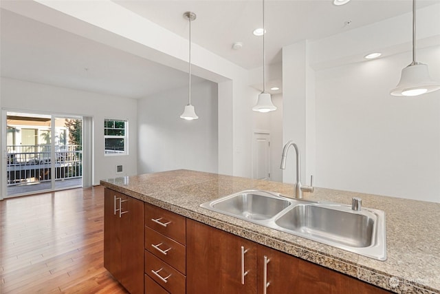 kitchen with sink, light hardwood / wood-style flooring, and hanging light fixtures