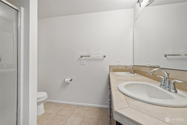 bathroom featuring tile patterned flooring, vanity, a shower with shower door, and toilet