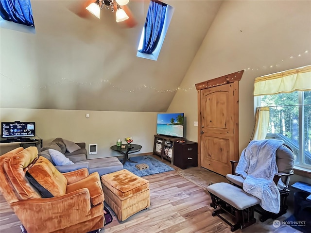 living room with vaulted ceiling with skylight and light hardwood / wood-style flooring