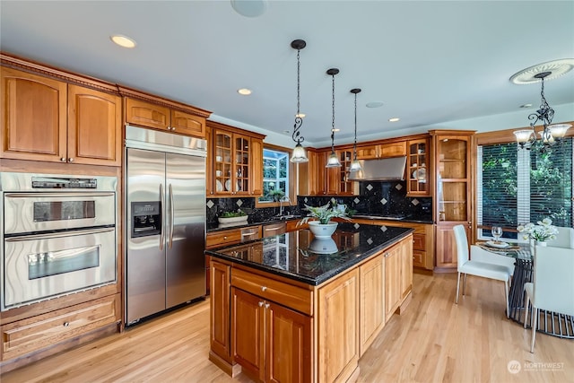 kitchen with pendant lighting, stainless steel appliances, a center island, and dark stone counters