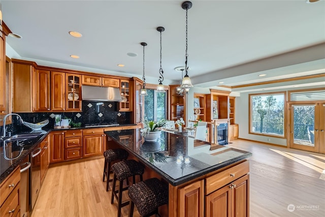 kitchen featuring a healthy amount of sunlight, sink, a kitchen island, and light wood-type flooring