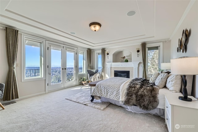 carpeted bedroom with a raised ceiling, access to outside, multiple windows, and french doors