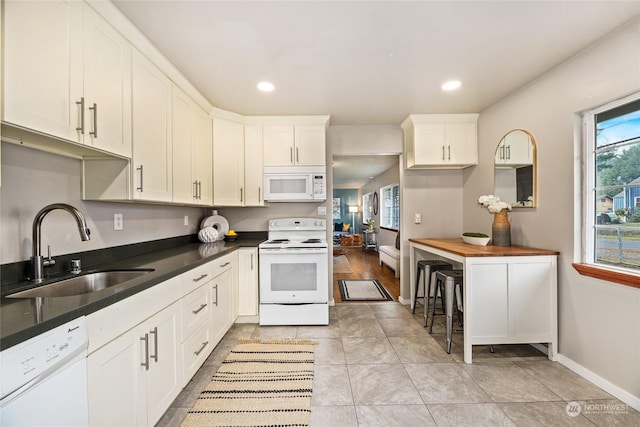 kitchen featuring sink, white appliances, light tile patterned floors, and white cabinets