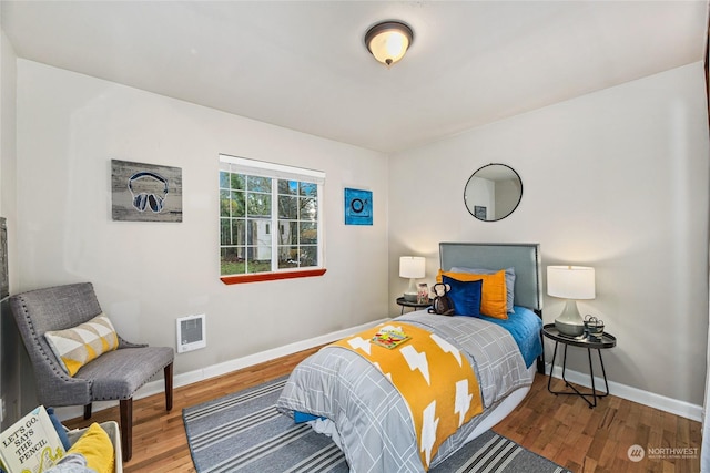 bedroom featuring heating unit and hardwood / wood-style flooring