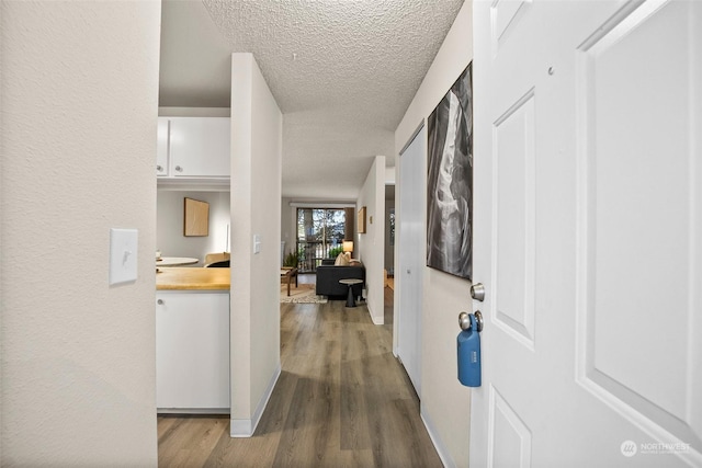 hallway with wood-type flooring and a textured ceiling