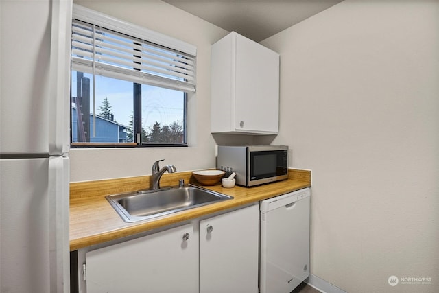 kitchen featuring refrigerator, sink, white cabinets, and white dishwasher