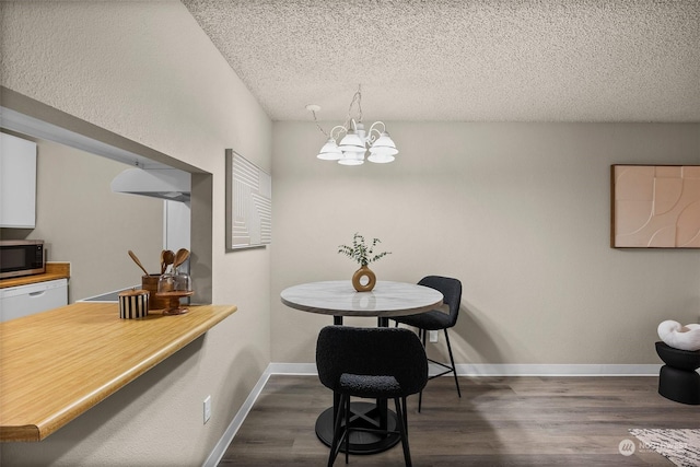 dining space with a textured ceiling, dark hardwood / wood-style floors, and a chandelier