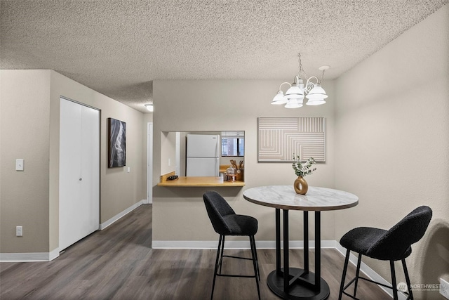 dining space featuring a notable chandelier, dark wood-type flooring, and a textured ceiling