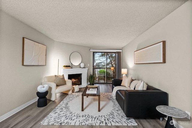 living room with hardwood / wood-style floors, a textured ceiling, and a brick fireplace