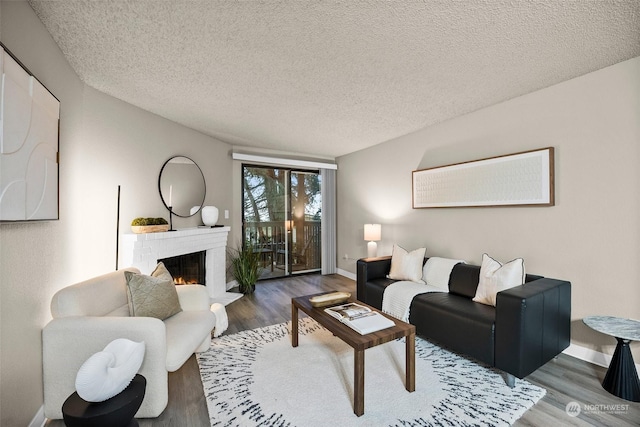 living room featuring wood-type flooring, a brick fireplace, and a textured ceiling