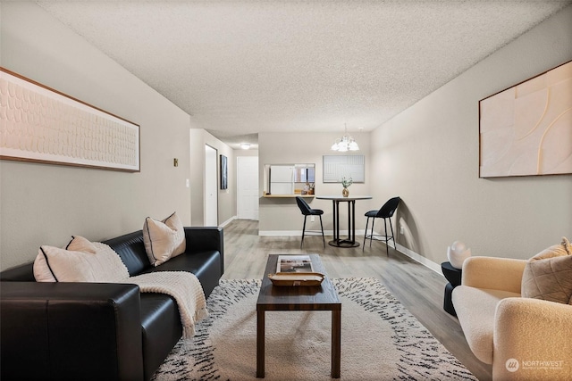 living room featuring hardwood / wood-style flooring, a notable chandelier, and a textured ceiling