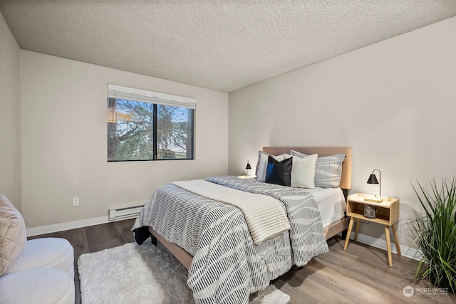 bedroom featuring wood-type flooring, a textured ceiling, and a baseboard heating unit