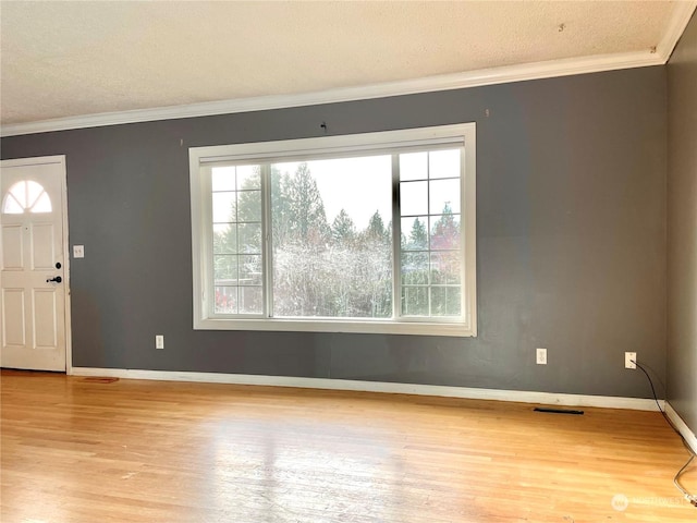 foyer entrance featuring a textured ceiling, ornamental molding, and light hardwood / wood-style floors