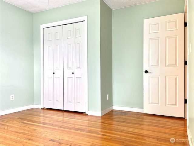 unfurnished bedroom featuring light wood-type flooring, a textured ceiling, and a closet