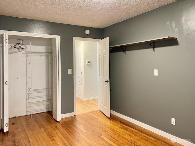 unfurnished bedroom featuring light hardwood / wood-style floors, a closet, and a textured ceiling