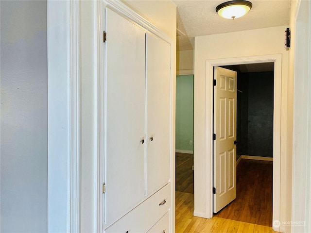 hallway featuring a textured ceiling and light hardwood / wood-style floors