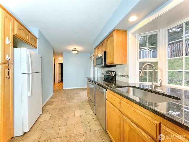 kitchen featuring dark stone countertops, appliances with stainless steel finishes, sink, and backsplash